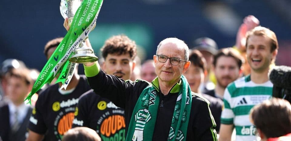 Entrenador levantando trofeo con jugadores sonrientes detrás