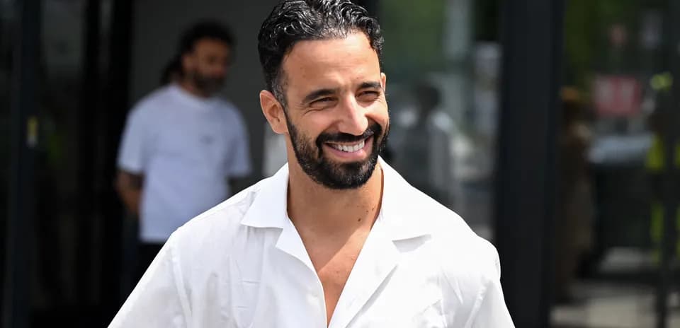 Hombre sonriendo con camisa blanca en exterior