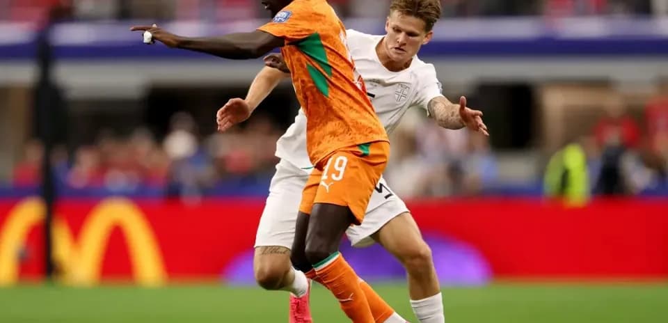Jugador con camiseta naranja driblando a oponente
