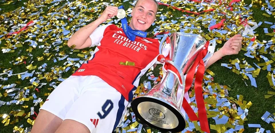 Jugadora de Arsenal con trofeo y medalla en el césped