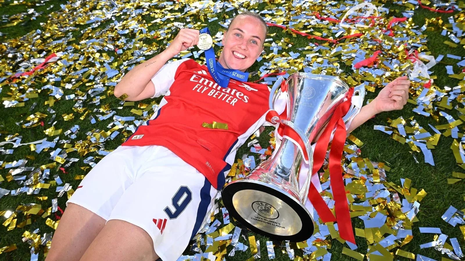 Jugadora de Arsenal con trofeo y medalla en el césped