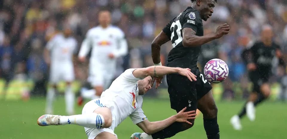Jugador de Tottenham driblando mientras otro cae al suelo