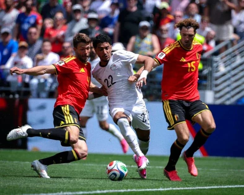 Jugador de Egipto esquivando a dos defensores de Bélgica