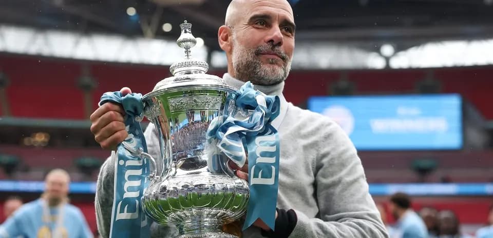 Entrenador sosteniendo trofeo en Wembley tras victoria