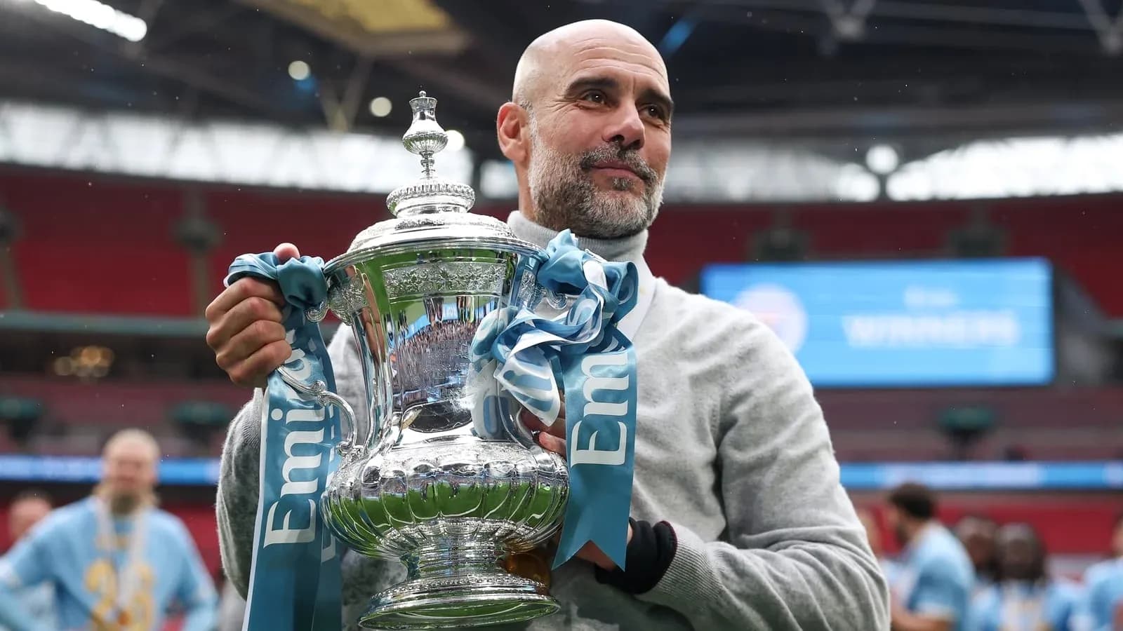 Entrenador sosteniendo trofeo en Wembley tras victoria