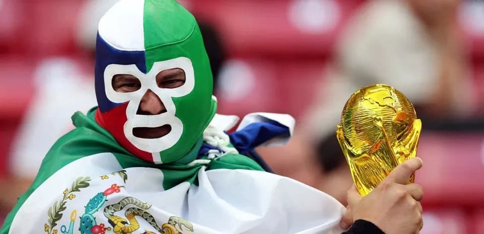 A fan wearing a mask holding the World Cup trophy