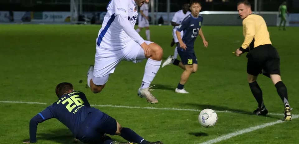 Jugador salta sobre oponente en partido de fútbol