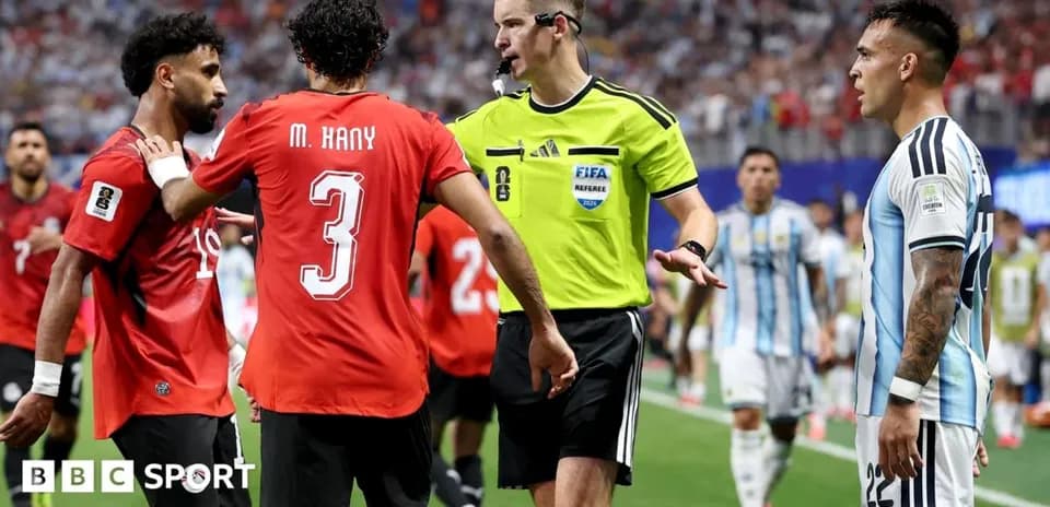 Jugadores y árbitro discutiendo durante partido de fútbol