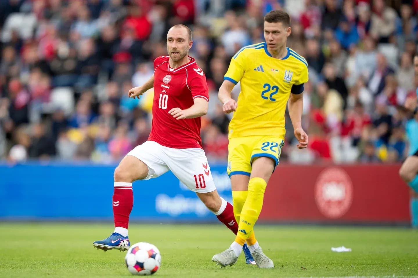 Jugador danés y ucraniano compiten por el balón