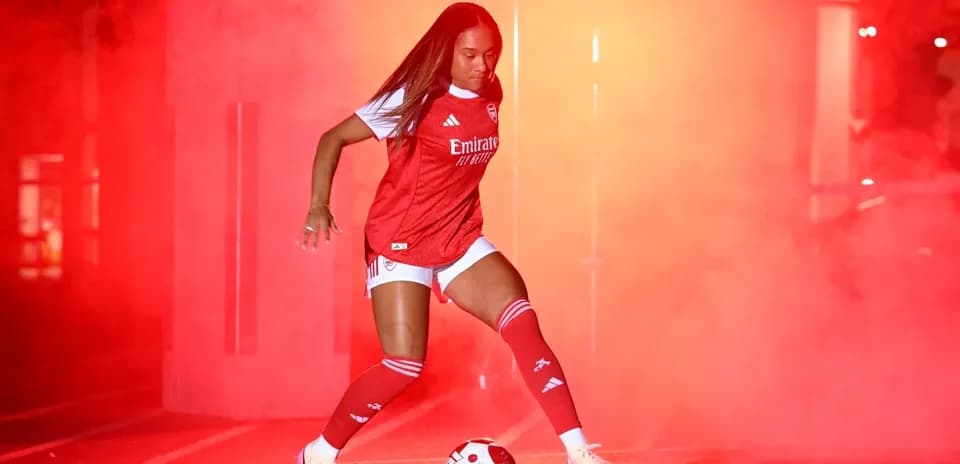 Jugadora de fútbol en acción con humo rojo