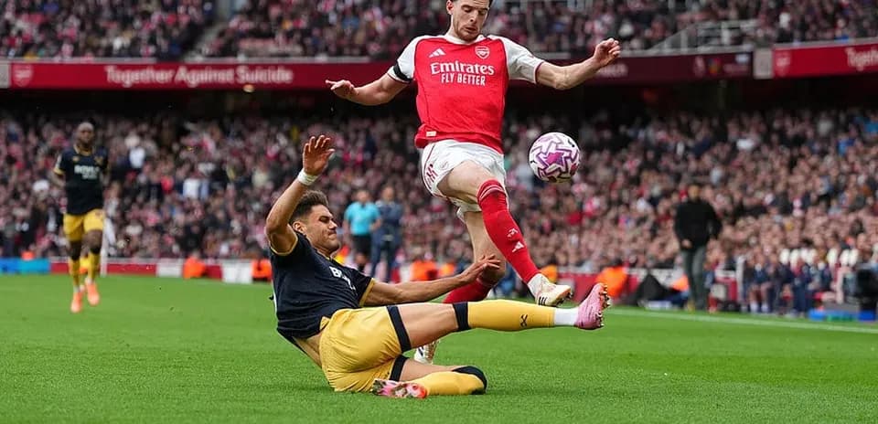 Jugador de Arsenal evitando una entrada de West Ham Jugador de Arsenal evitando una entrada de West Ham