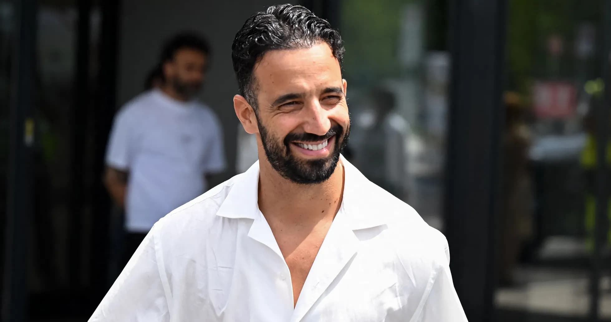 Hombre sonriendo con camisa blanca en exterior Hombre sonriendo con camisa blanca en exterior