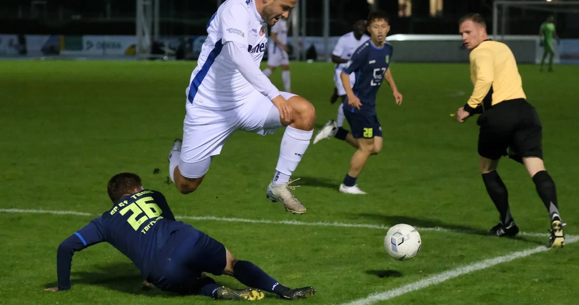 Jugador salta sobre oponente en partido de fútbol Jugador salta sobre oponente en partido de fútbol